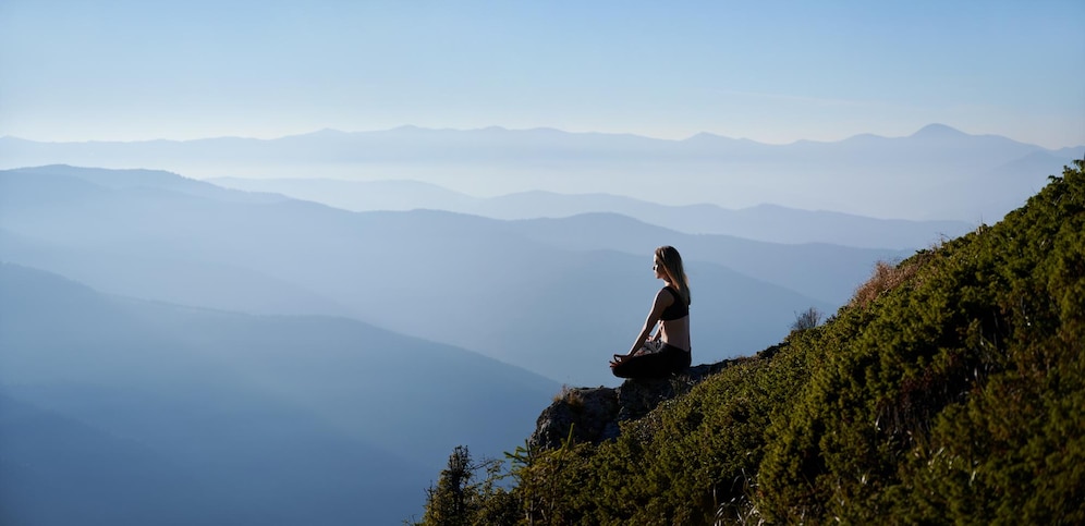sporty-young-woman-meditating-mountains_651396-2676